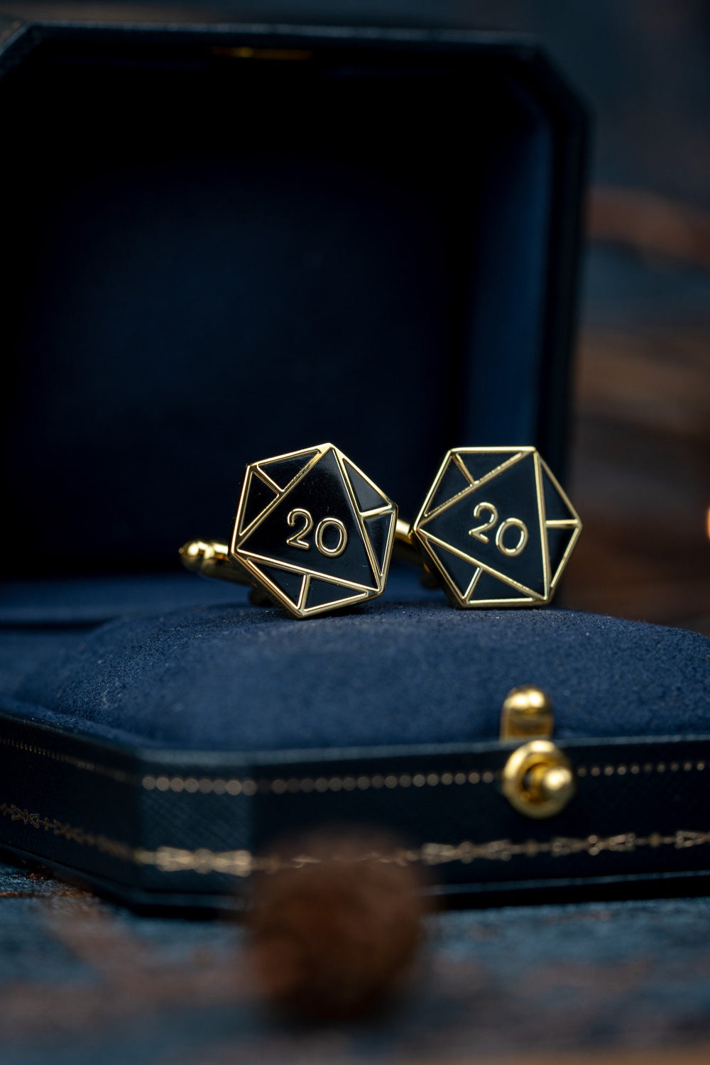 Gold D20 Cufflinks with black enamel sitting in a gift box.