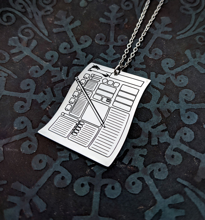 Silver character sheet pendant necklace on a dark fantasy-themed background. Ideal TTRPG character sheet jewelry for D&D players who love fantasy-inspired accessories.