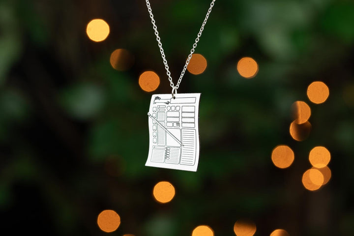 Silver character sheet necklace with blurred bokeh lights. Fantasy-inspired TTRPG necklace, ideal for Dungeons & Dragons and RPG jewelry lovers.